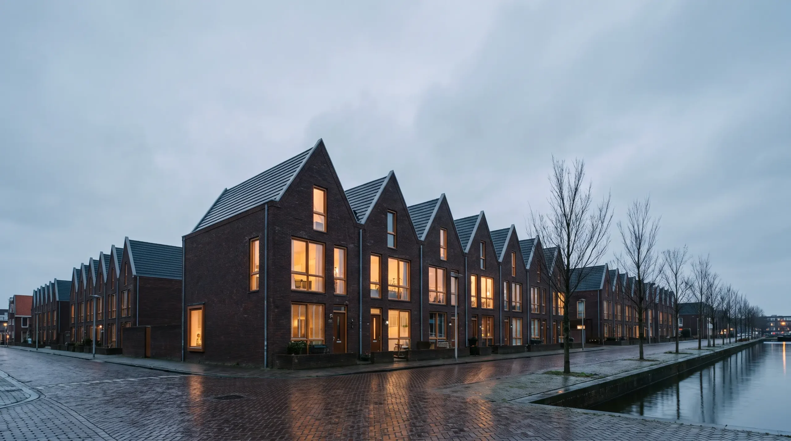 Rij Nederlandse bakstenen woningen met puntgevels in de avondschemering